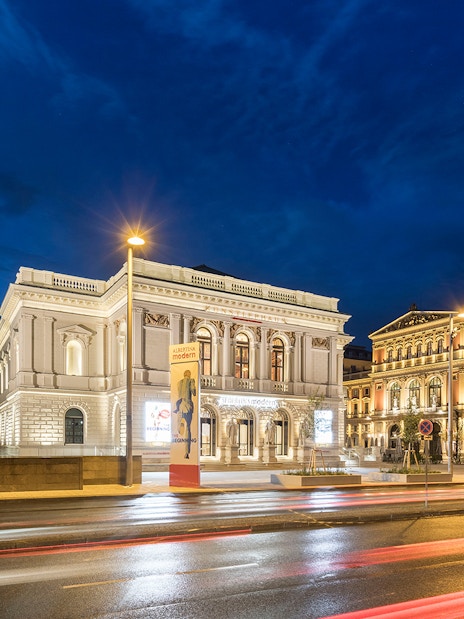 ALBERTINA MODERN museum in Vienna illuminated at night with street view.