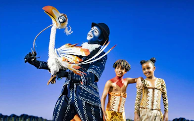 Lion King West End performers with Zazu puppet on stage.