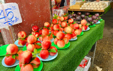 Fresh peaches and plums on display at a Chiang Mai market during the Michelin Food Walking Tour.