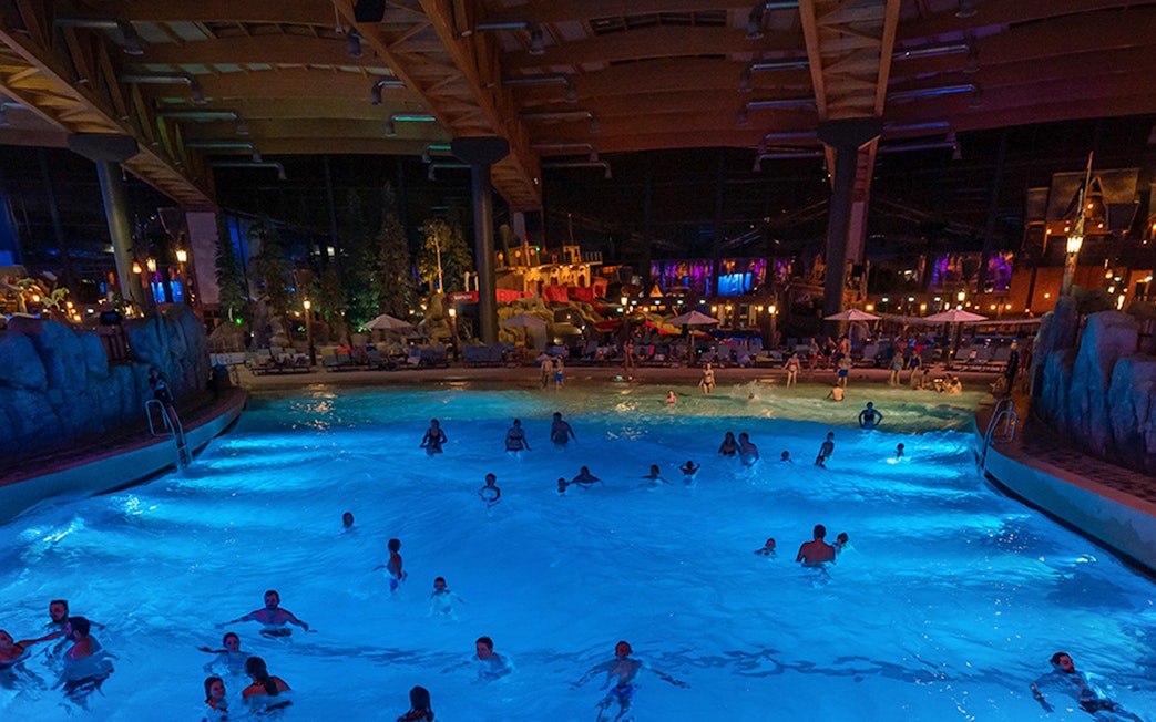 Indoor wave pool with people swimming at Rulantica water park, Germany.