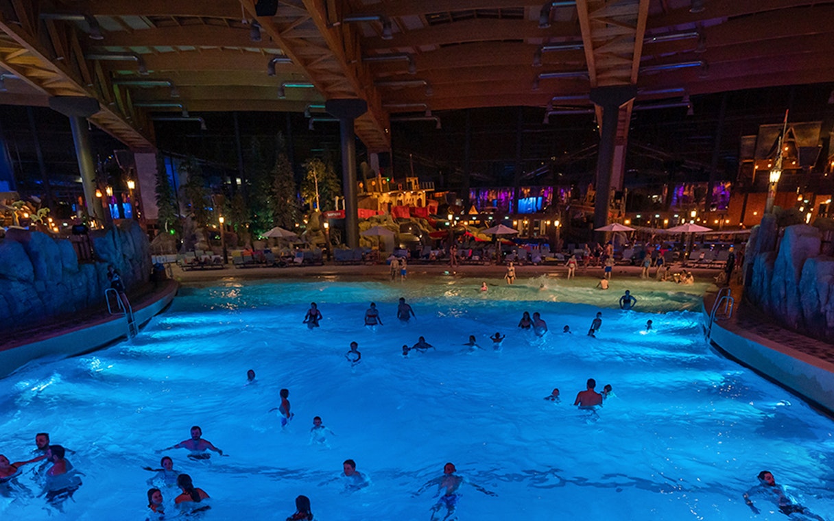 Indoor wave pool with people swimming at Rulantica water park, Germany.