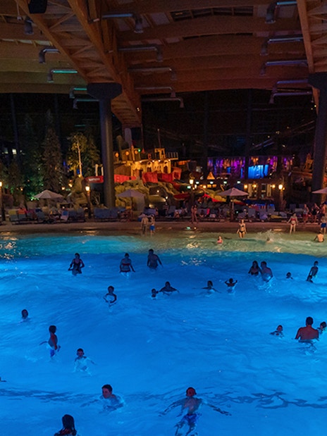 Indoor wave pool with people swimming at Rulantica water park, Germany.