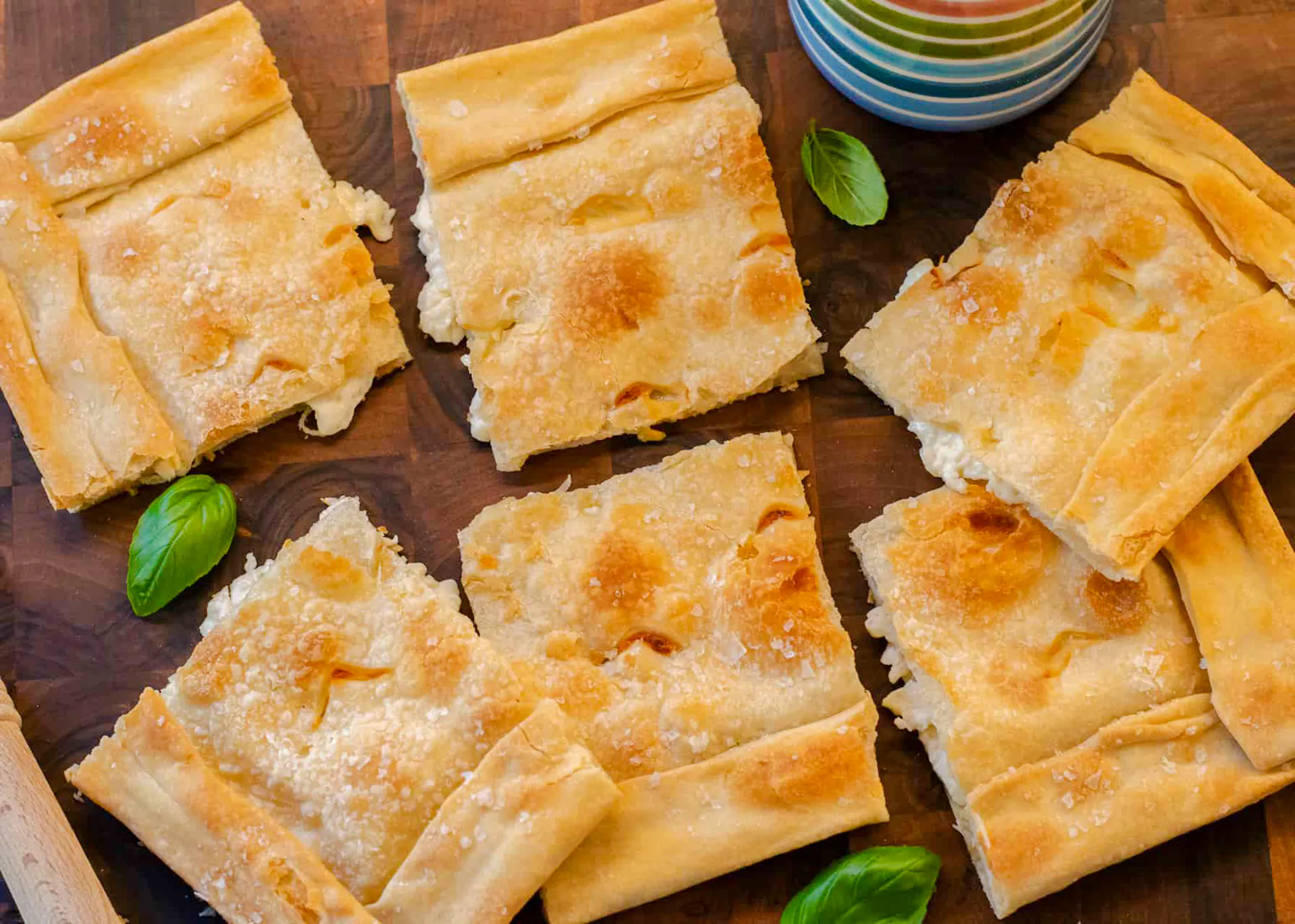 Focaccia di Recco slices on a wooden board during a Genoese cooking lesson in Genoa.