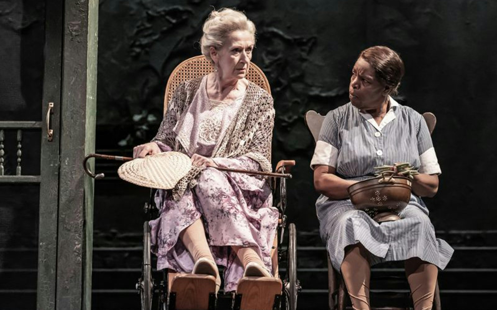 Elderly woman in a wheelchair and a woman in a maid uniform on stage, "To Kill A Mockingbird" play.