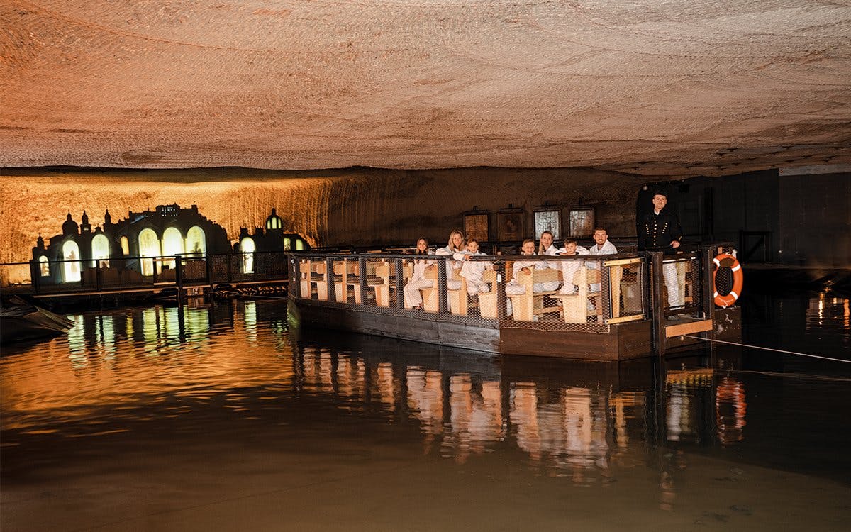 Boat tour inside Hallein salt mines, Salzburg, with visitors exploring illuminated underground caverns.