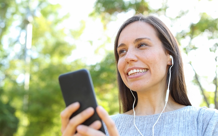 Woman listening to audioguide on phone during Château of Chantilly tour.