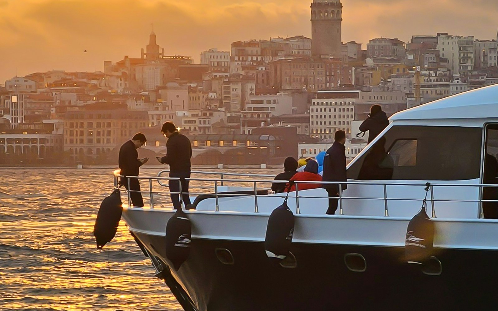 Bosphorus yacht cruise at sunset with drinks and canapes, Istanbul skyline in background.