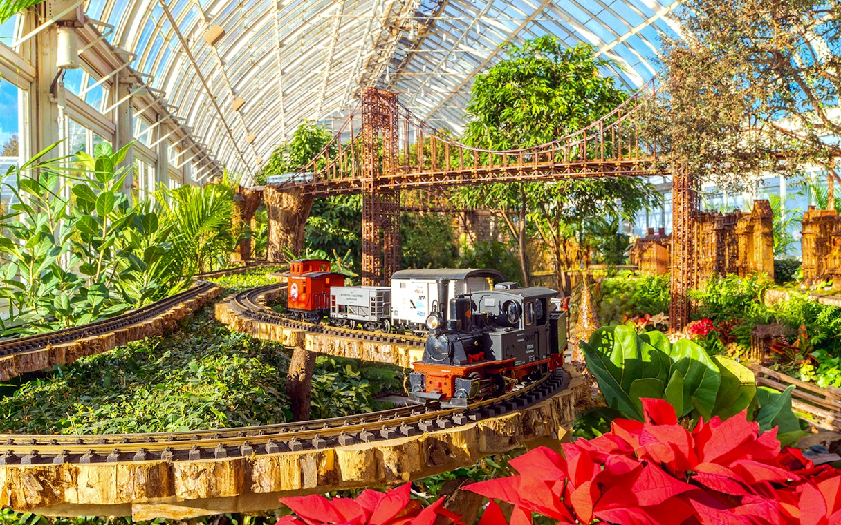Model trains on tracks with festive decorations at New York Botanical Gardens.