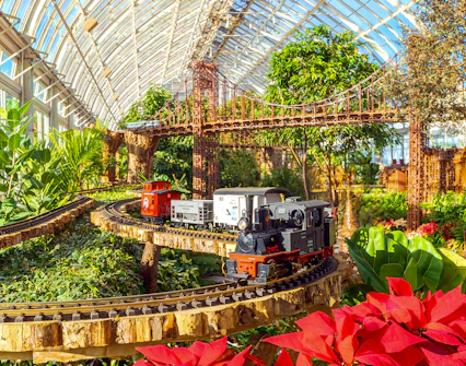 Model trains on tracks with festive decorations at New York Botanical Gardens.