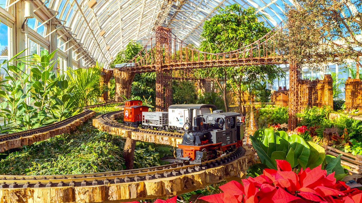 Model trains on tracks with festive decorations at New York Botanical Gardens.