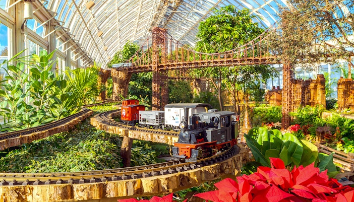 Model trains at New York Botanical Gardens Holiday Train Show with festive decorations.