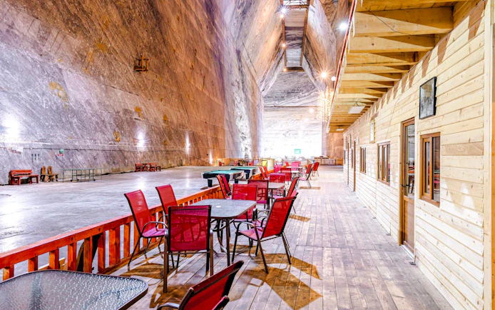 Seating area inside Slanic Salt Mine with wooden walls and tables.