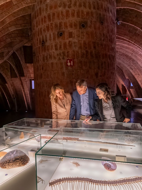 Tourist with guide examining artifacts in Casa Mila museum, Barcelona.