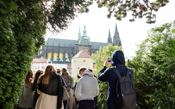 Group touring Prague Castle grounds with view of cathedral spires.