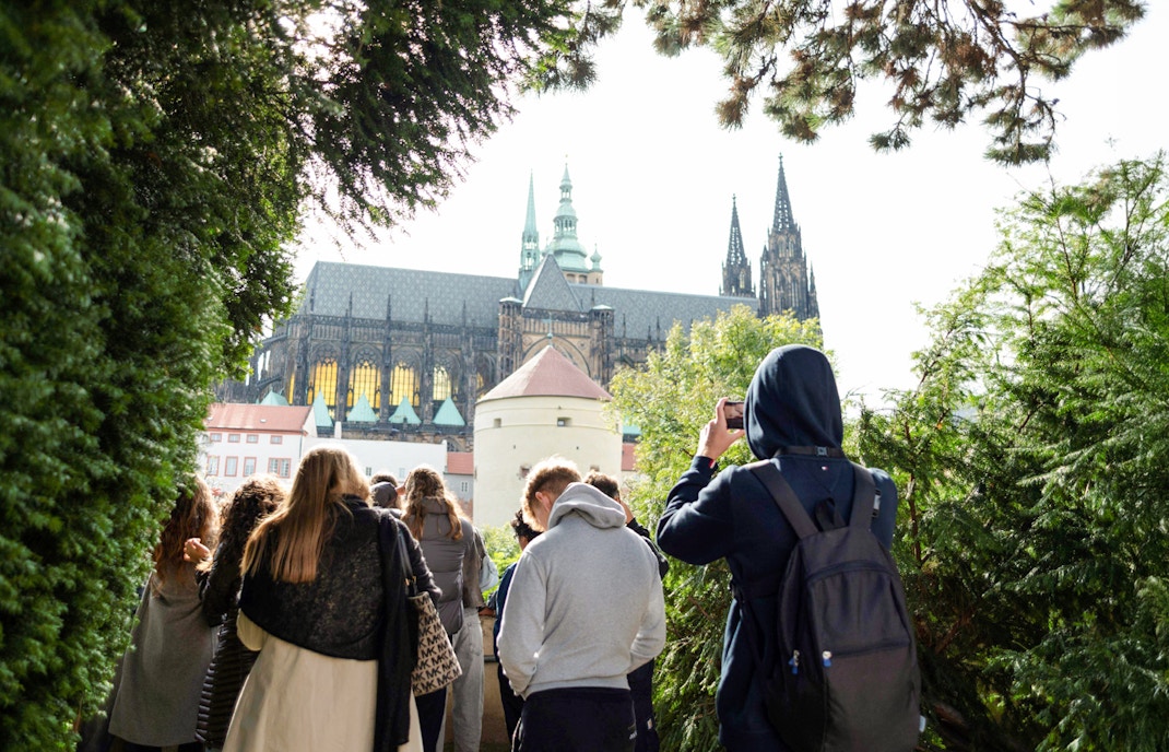 Group touring Prague Castle grounds with view of cathedral spires.