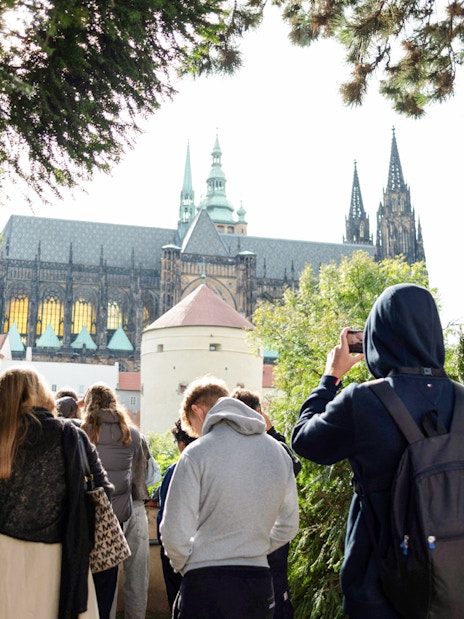 Group touring Prague Castle grounds with view of cathedral spires.