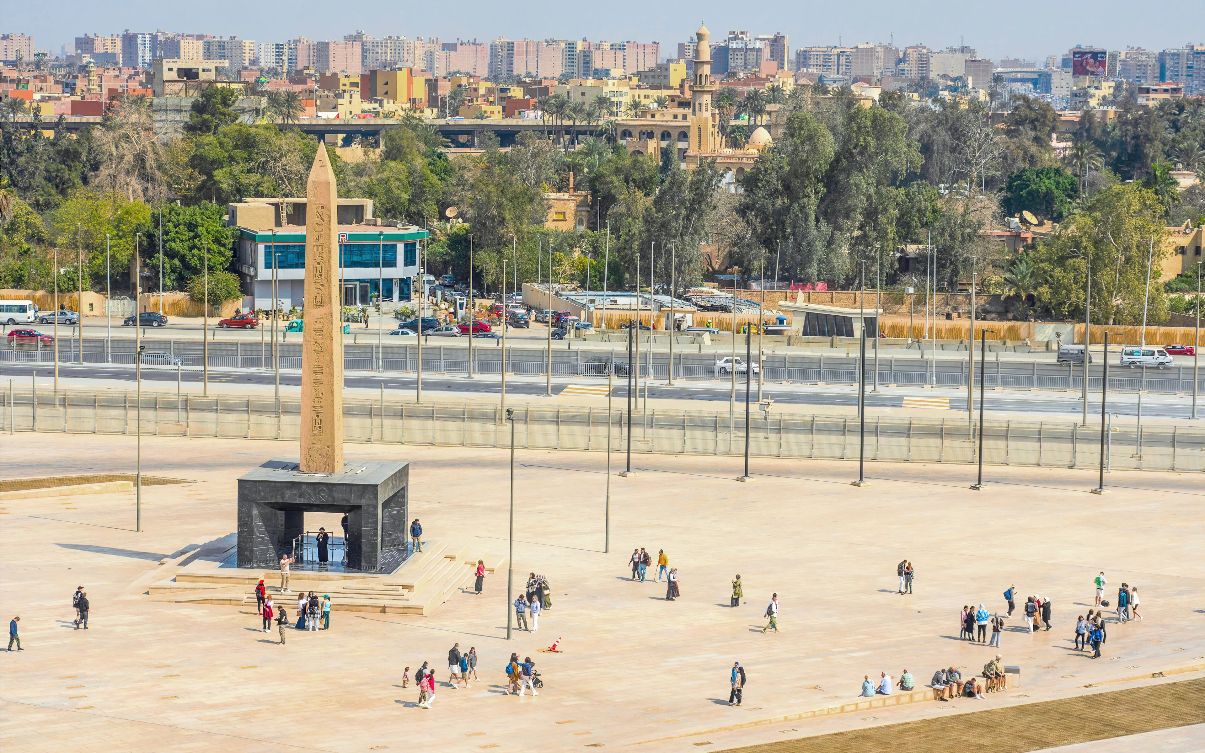 Hanging Obelisk at Grand Egyptian Museum with visitors exploring the plaza.