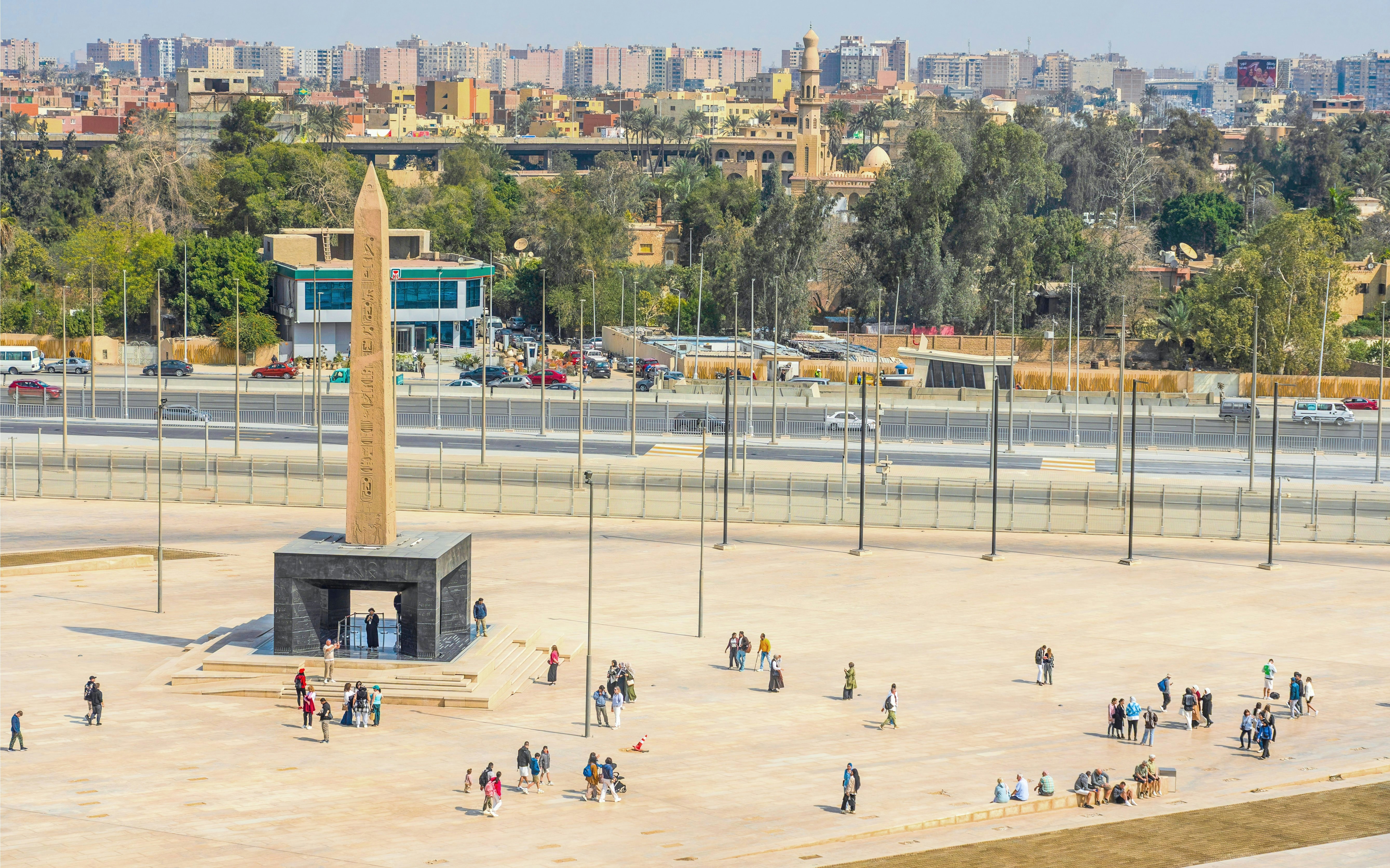 Hanging Obelisk at Grand Egyptian Museum with visitors exploring the plaza.