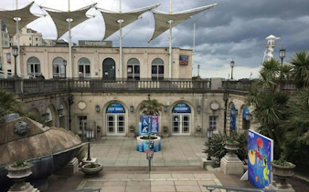 Brighton seafront entrance with palm trees and colorful mural, part of self-guided city exploration game.