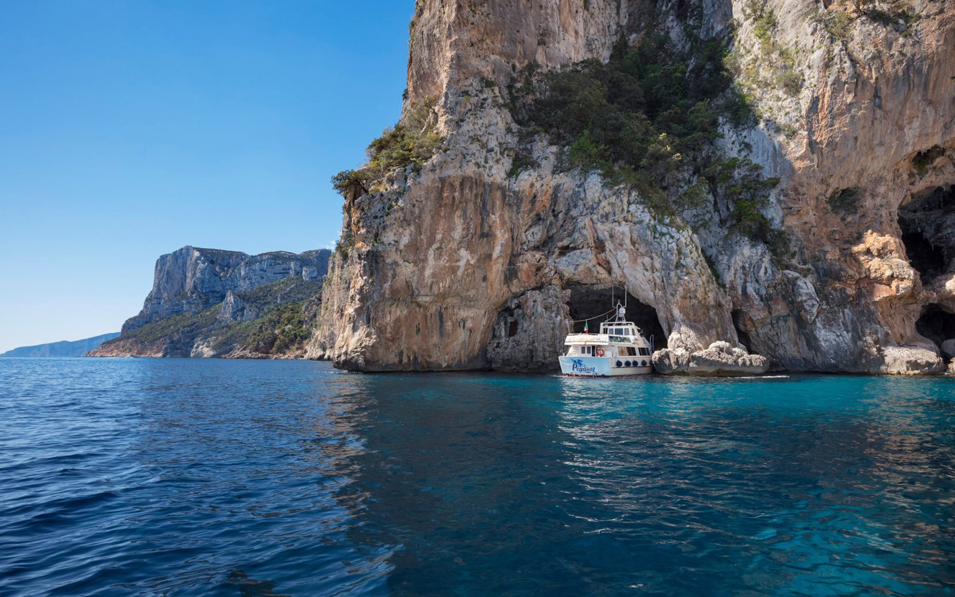 Boat approaching cave entrance at Gulf of Orosei, Italy.
