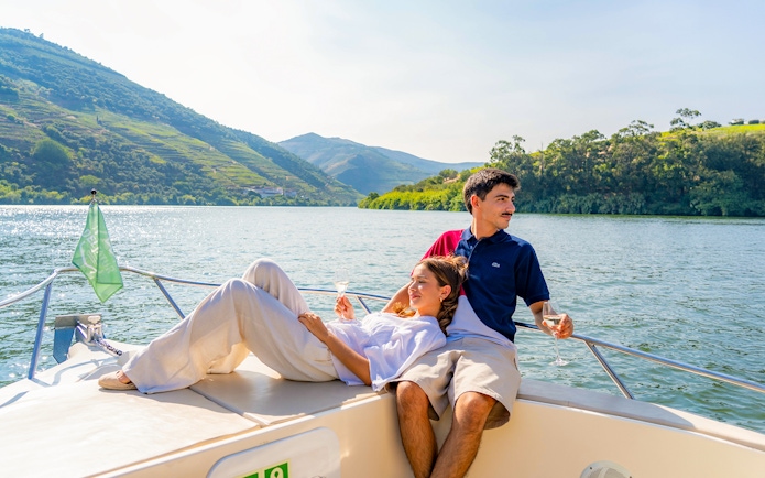 Couple enjoying wine on a boat in Douro Valley tour, Portugal.