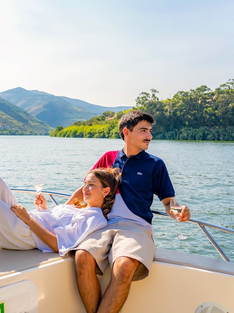 Couple enjoying wine on a boat in Douro Valley tour, Portugal.