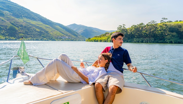 Couple enjoying wine on a boat in Douro Valley tour, Portugal.