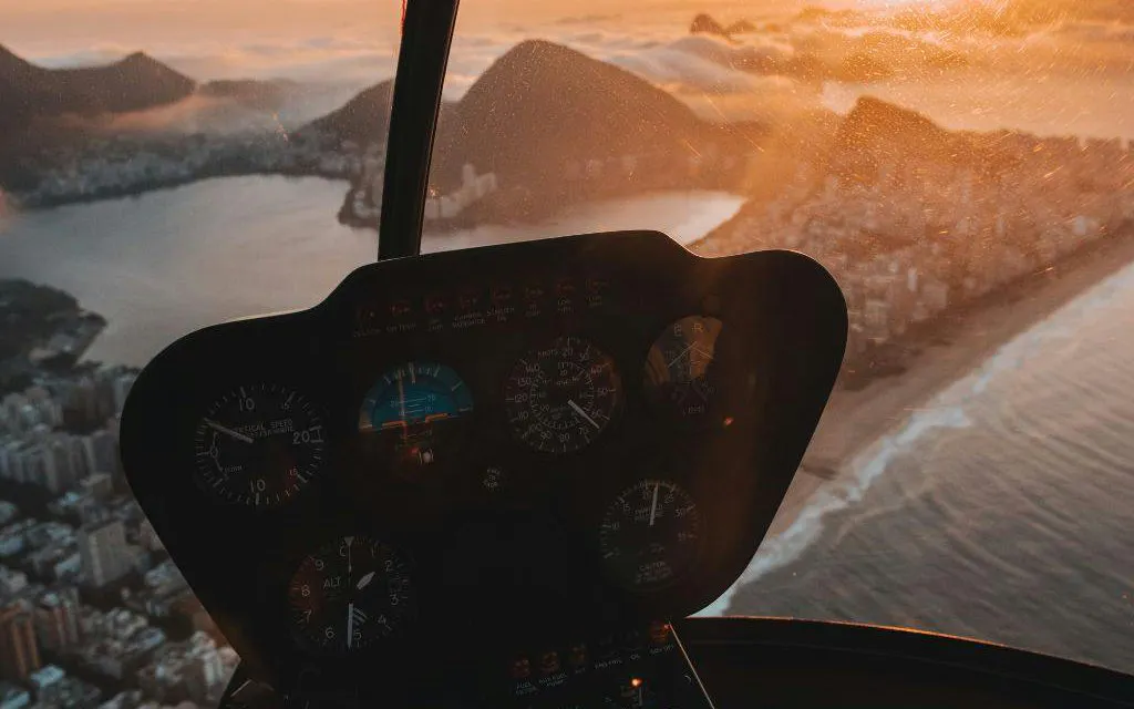 Helicopter cockpit view of Rio de Janeiro coastline at sunset during VIP tour.