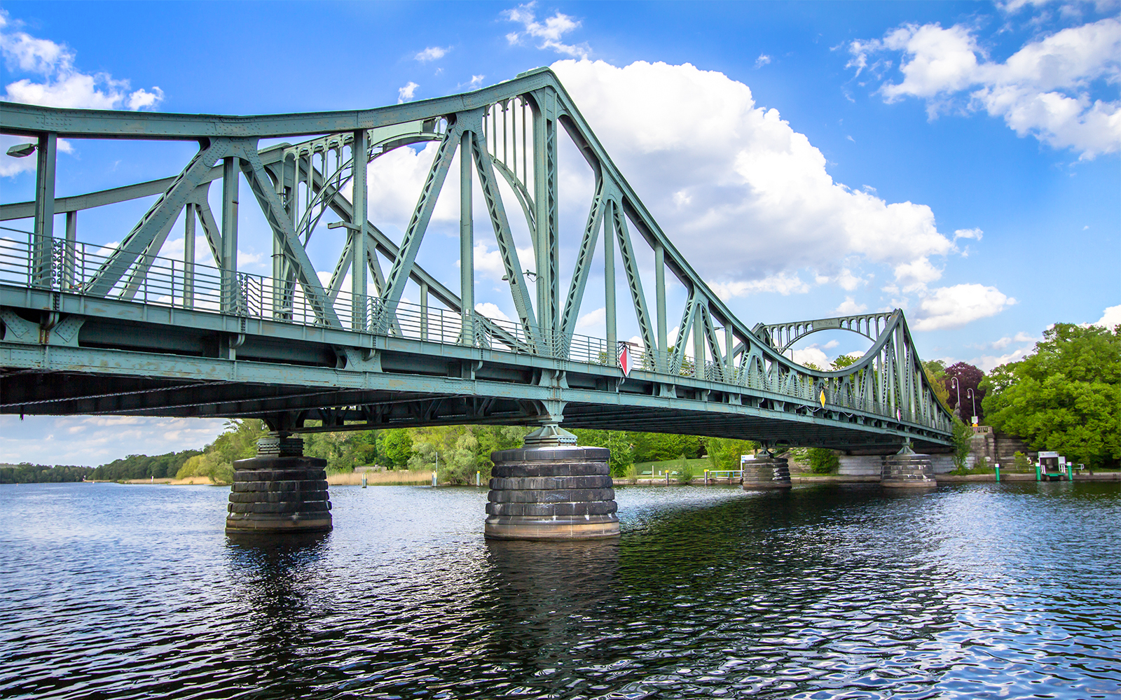 Glienicke Bridge spanning the Havel River in Berlin, surrounded by lush greenery.