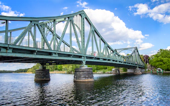 Glienicke Bridge spanning the Havel River in Berlin, surrounded by lush greenery.