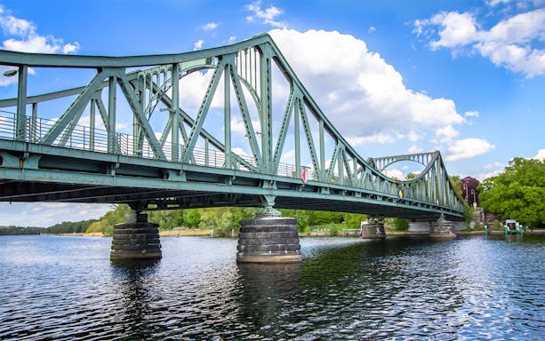 Glienicke Bridge spanning the Havel River in Berlin, surrounded by lush greenery.