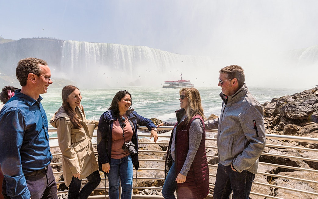 Tourists gathered at Niagara Falls with a boat in the background.