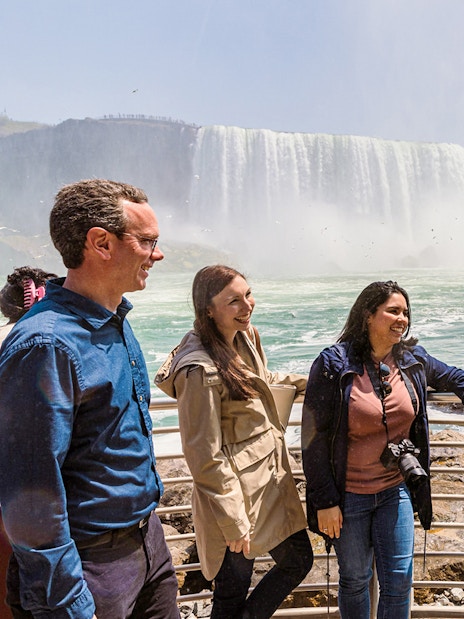 Tourists gathered at Niagara Falls with a boat in the background.