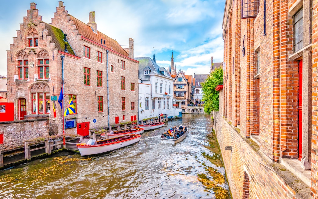 Boat trip on Bruges canal with historic brick buildings and tourists.
