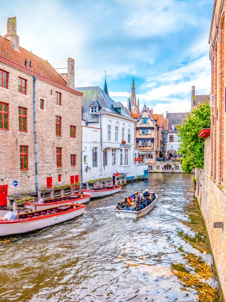Boat trip on Bruges canal with historic brick buildings and tourists.