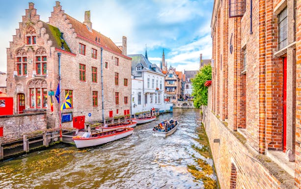 Boat trip on Bruges canal with historic brick buildings and tourists.