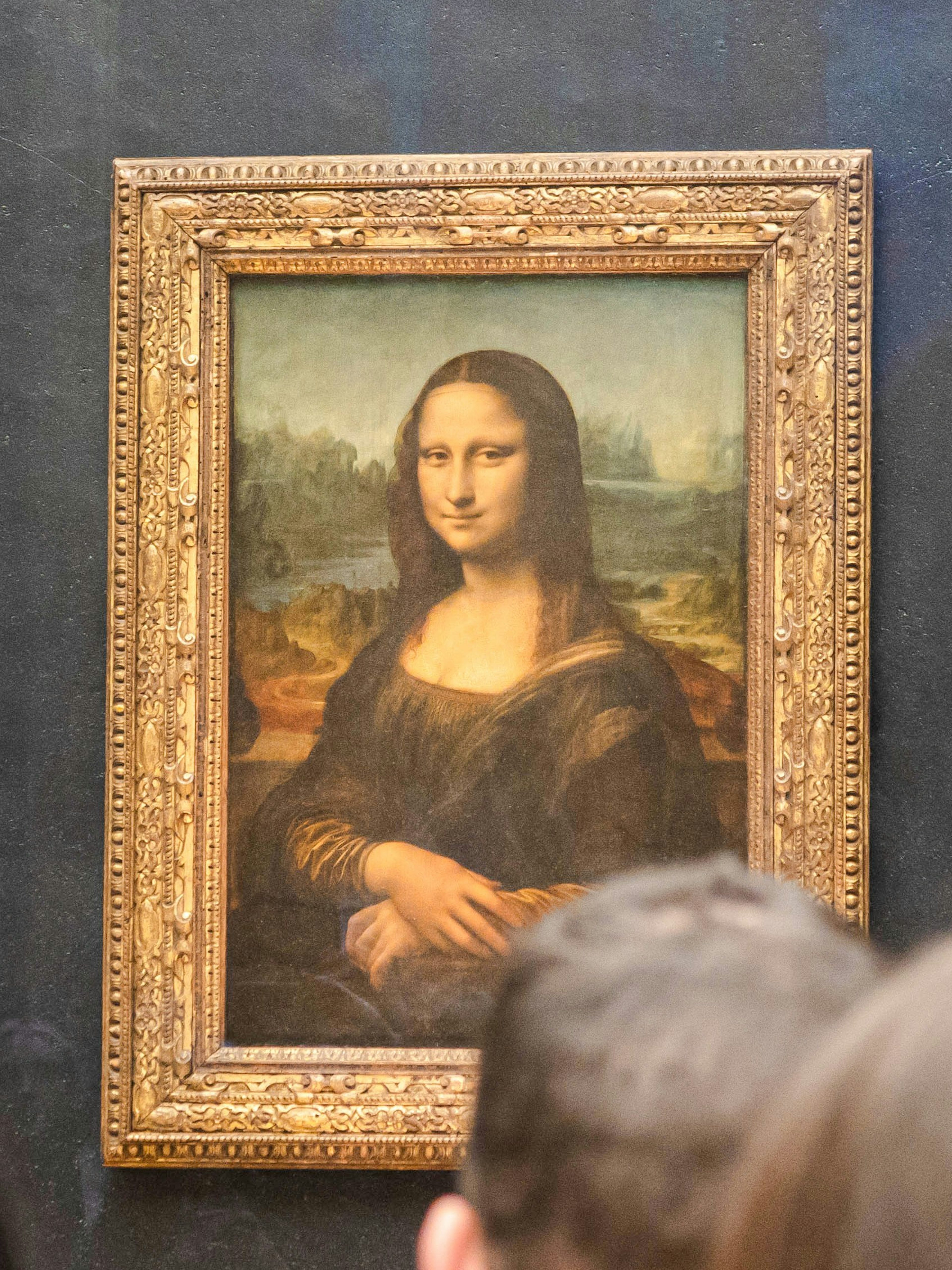 Mona Lisa displayed at the Louvre Museum, Paris, with visitors viewing the painting.