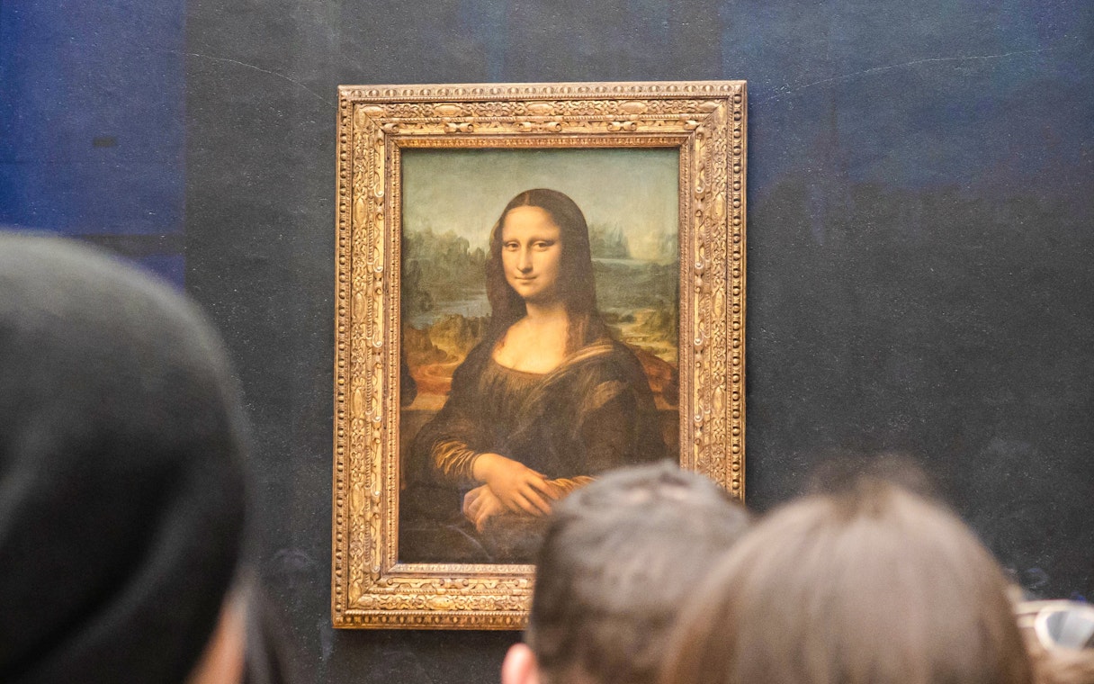 Mona Lisa displayed at the Louvre Museum, Paris, with visitors viewing the painting.
