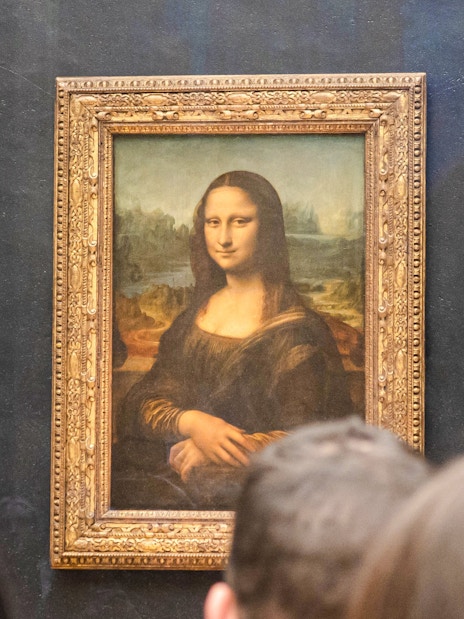 Mona Lisa displayed at the Louvre Museum, Paris, with visitors viewing the painting.