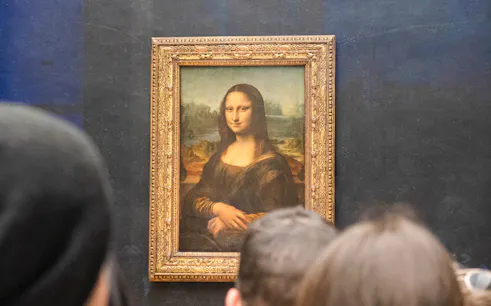 Mona Lisa displayed at the Louvre Museum, Paris, with visitors viewing the painting.