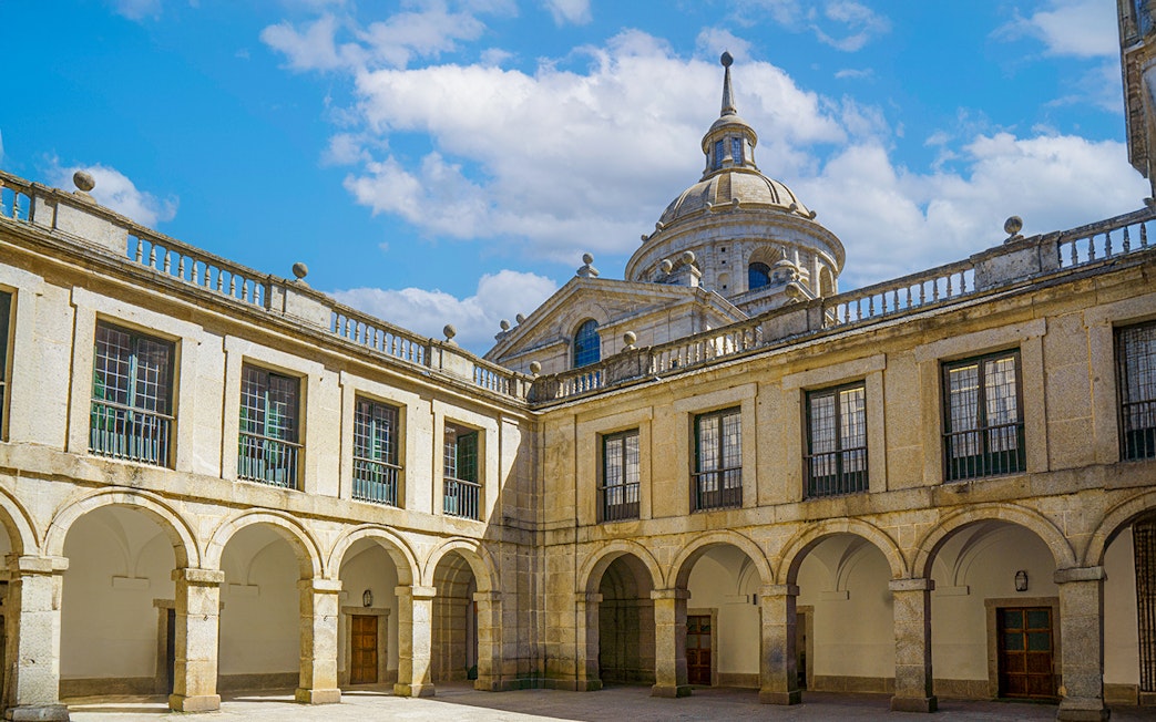 Courtyard of the Royal Monastery of San Lorenzo del Escorial with arched walkways.