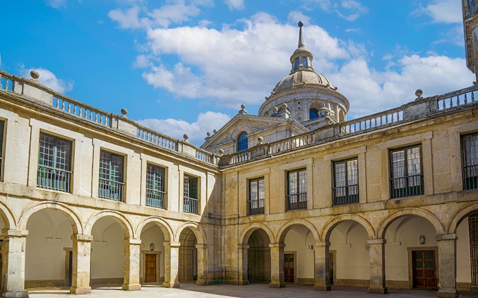 Courtyard of the Royal Monastery of San Lorenzo del Escorial with arched walkways.