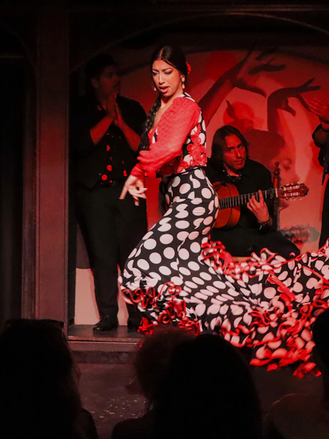 Flamenco dancer performing at El Duende by Tablao Cordobes with musicians in the background.