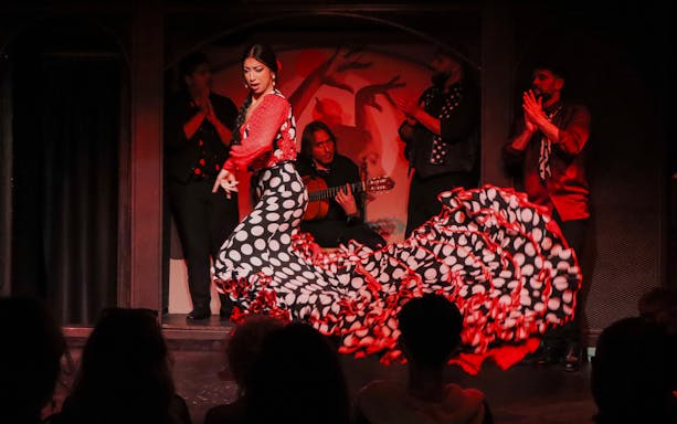 Flamenco dancer performing at El Duende by Tablao Cordobes with musicians in the background.