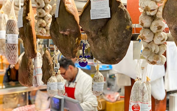 Hanging cured meats and garlic at a local market in Florence.