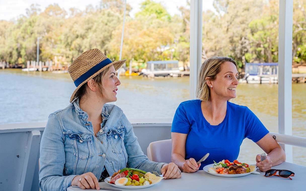 Two people enjoying lunch on a Murray River cruise with scenic river views.