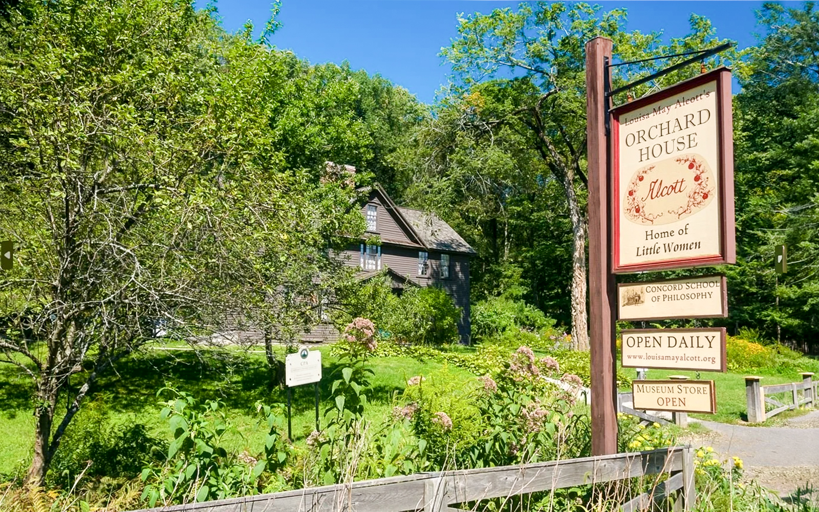 Alcott Orchard House with sign in Boston, Massachusetts, surrounded by lush greenery.