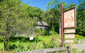 Alcott Orchard House with sign in Boston, Massachusetts, surrounded by lush greenery.