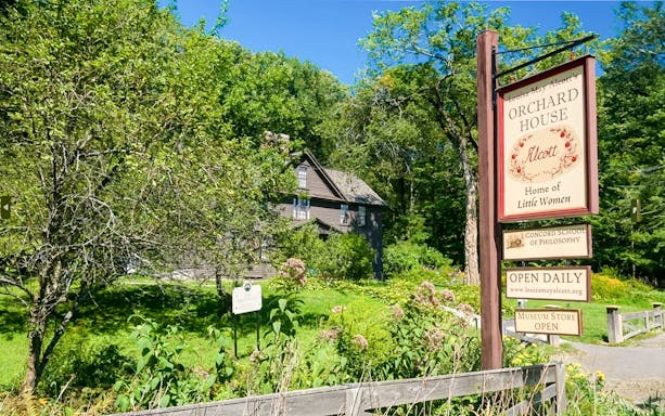 Alcott Orchard House with sign in Boston, Massachusetts, surrounded by lush greenery.