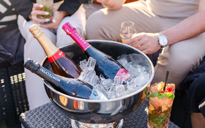 Champagne bottles in ice bucket with friends enjoying drinks on Prague yacht.